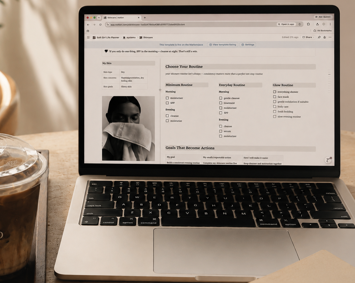 Laptop on a desk with a coffee cup and notebook, displaying a website.